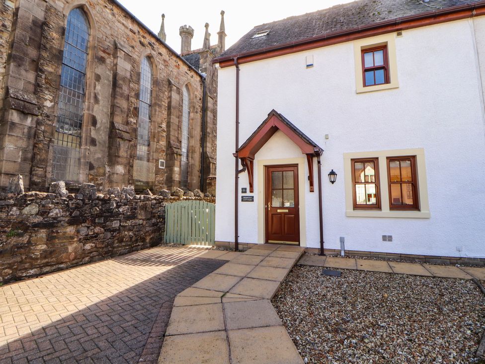An outdoor view of a house with a pathway and gate at Derwent Cottage in Cockermouth