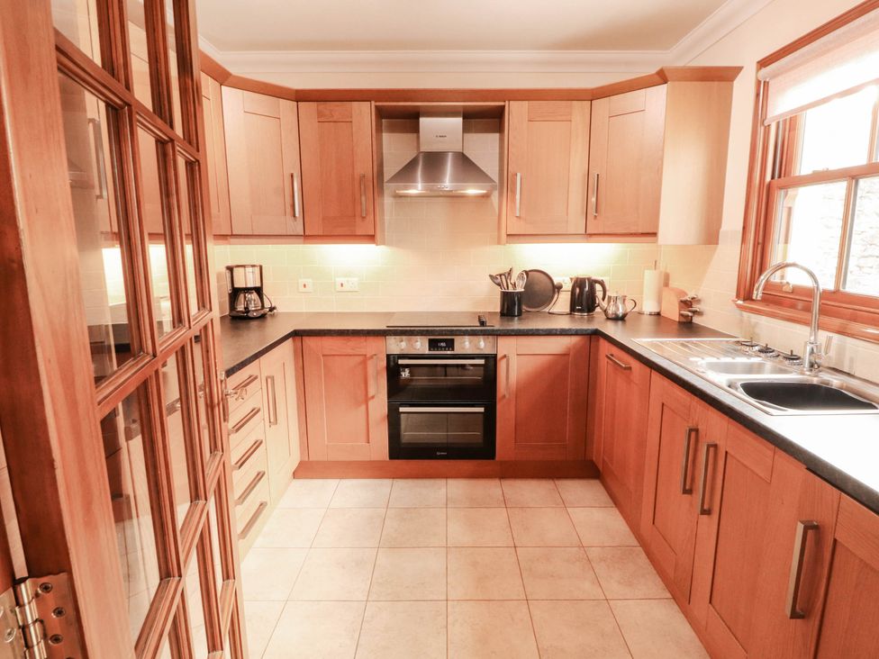 A kitchen with wood cabinets and appliances at Derwent Cottage in Cockermouth