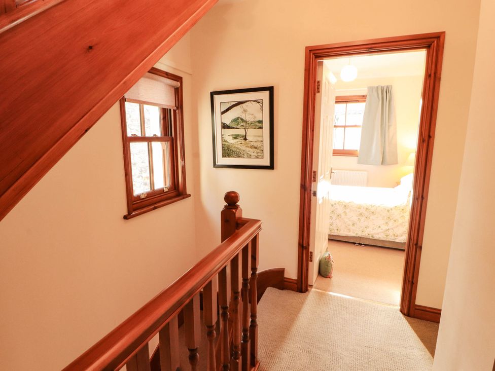 A hallway with a staircase and door leading to a bedroom at Derwent Cottage Cockermouth