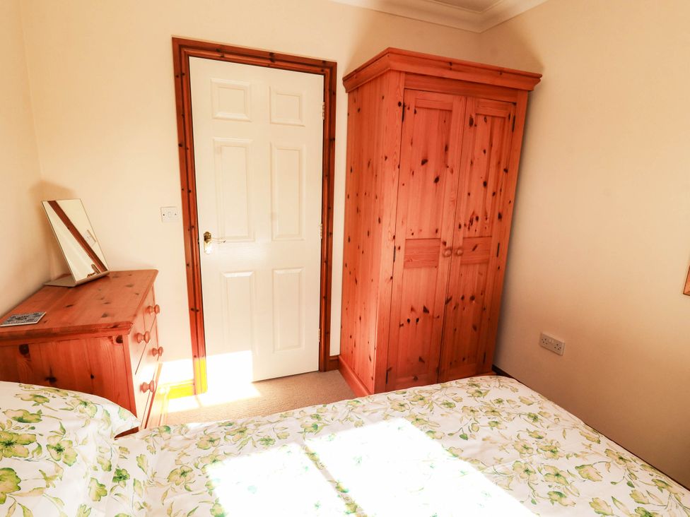A bedroom with a bed and wardrobe at Derwent Cottage in Cockermouth