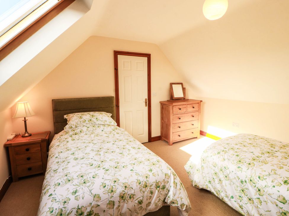 A bedroom with two beds and a dresser at Derwent Cottage in Cockermouth