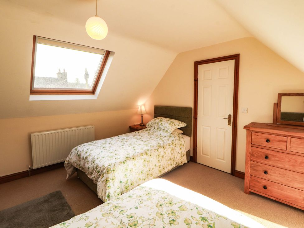 A bedroom with two beds and a chest of drawers at Derwent Cottage Cockermouth