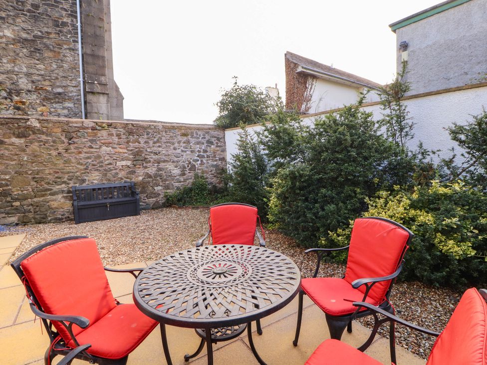 A garden with a table and chairs and a bench at Derwent Cottage in Cockermouth