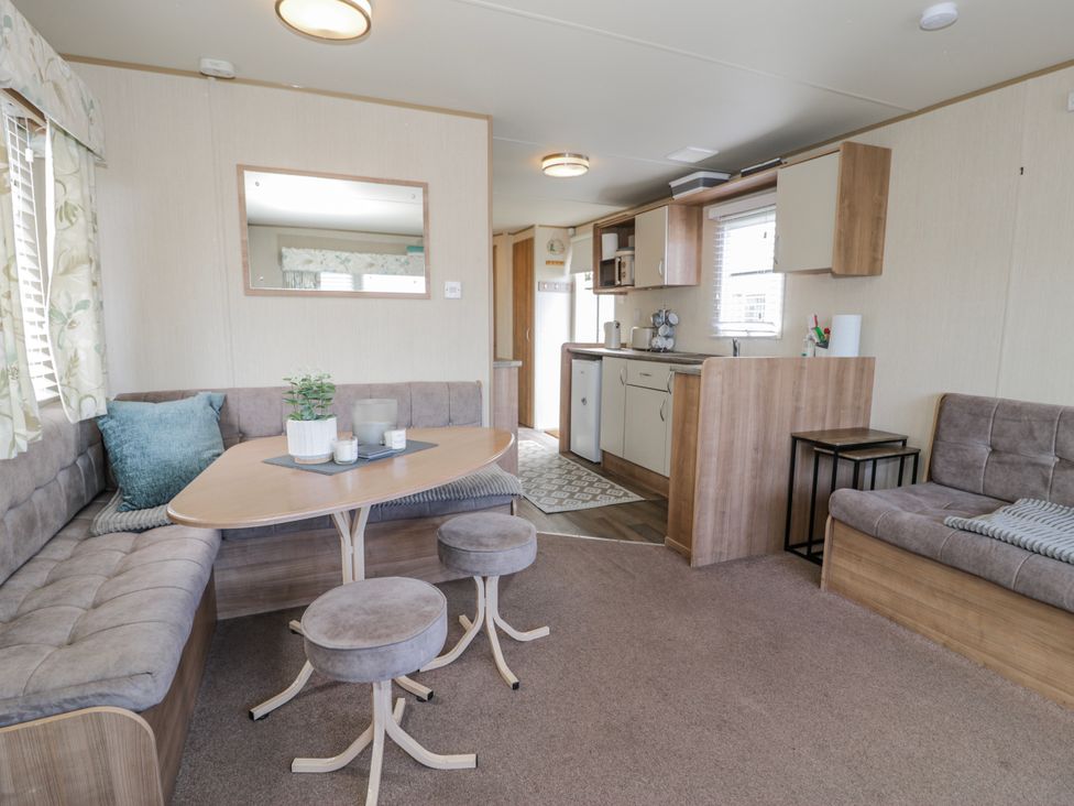A living room with a sofa, table, and kitchen area at 51 Silverbirch Way, Rhyl
