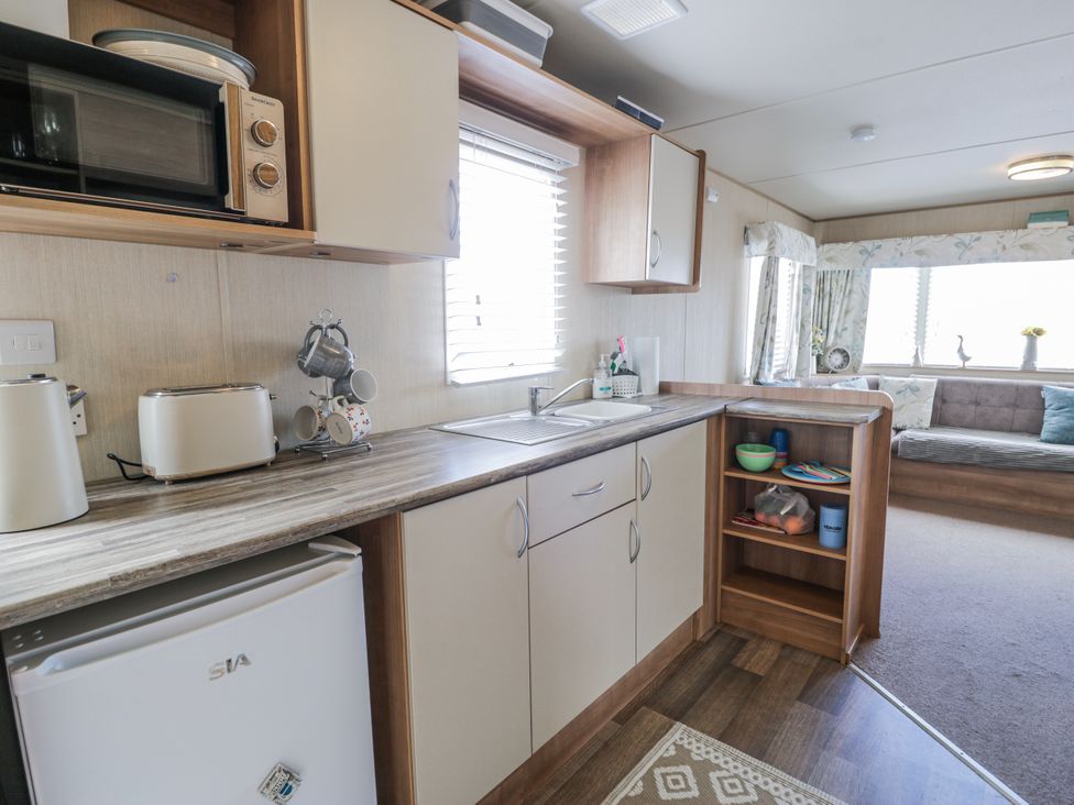 A kitchen area with appliances and sink at 51 Silverbirch Way in Rhyl
