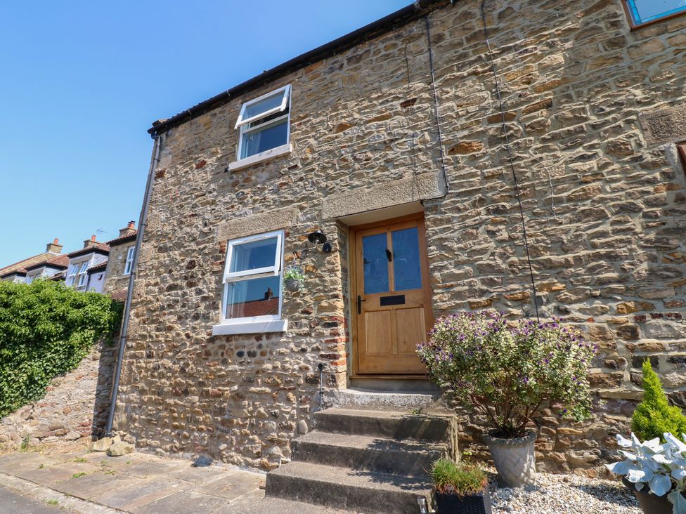 A stone house exterior with a front door and plants at 14 The Porch in Barton