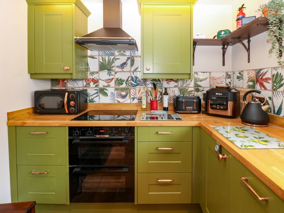 A kitchen with green cabinets and appliances at 14 The Porch in Barton