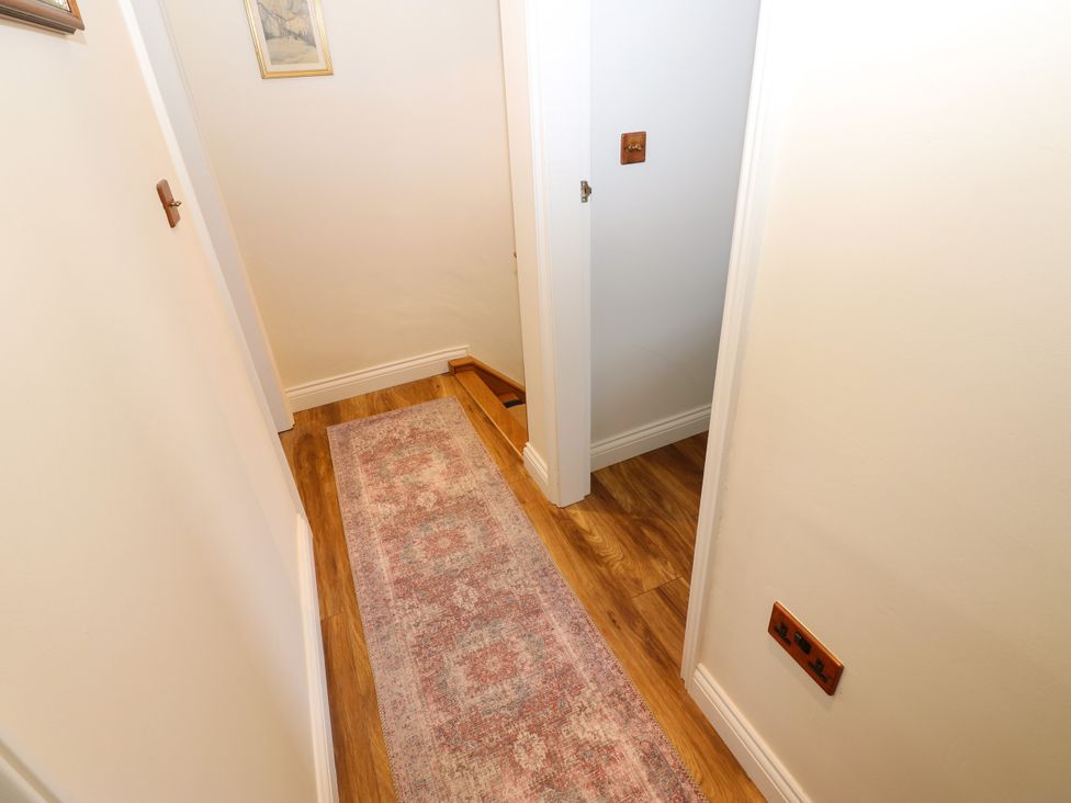 A hallway with a rug and doors at 14 The Porch in Barton
