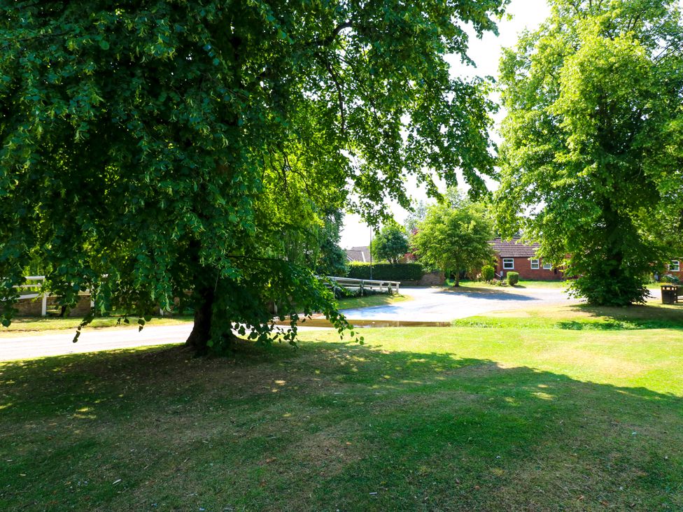 A view of a grassy area with trees and a building at 14 The Porch in Barton