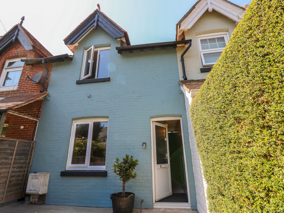 A front view of a blue house with a door and hedge at 8 Manor Villas Totland Bay