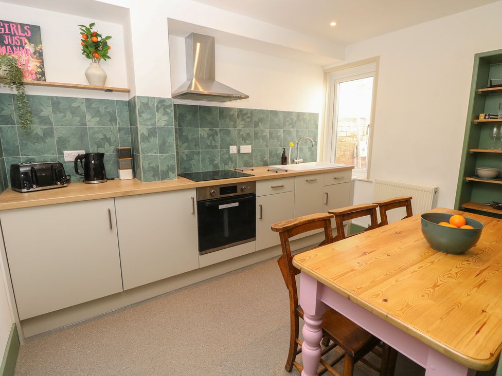 A kitchen with cabinets, a table, chairs, and appliances at 8 Manor Villas in Totland Bay