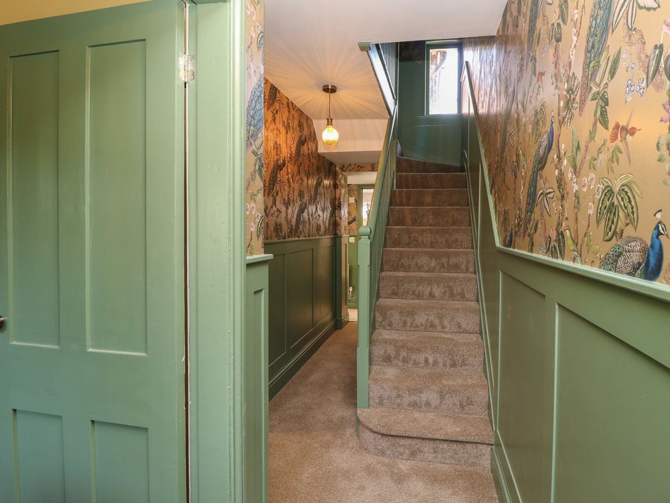 A hallway with a staircase and decorative wallpaper at 8 Manor Villas Totland Bay
