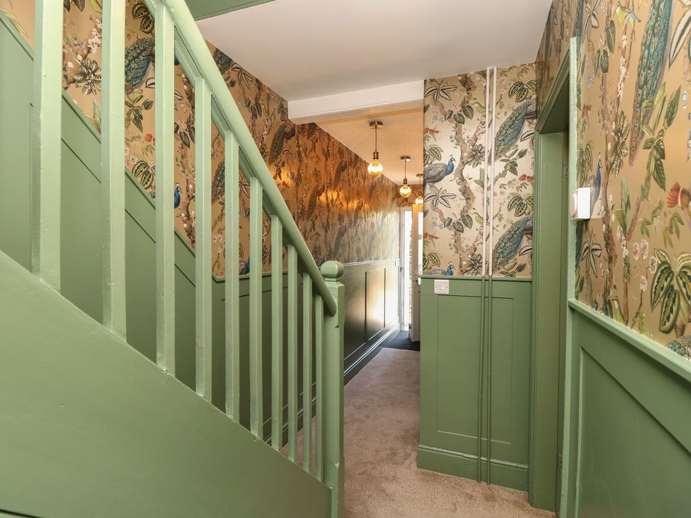 A hallway with a staircase and patterned wallpaper at 8 Manor Villas Totland Bay