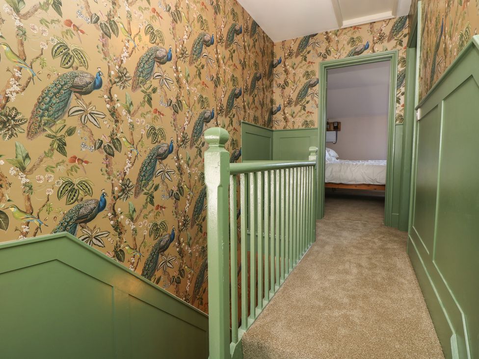 A staircase with patterned wallpaper and door leading to a room at 8 Manor Villas Totland Bay