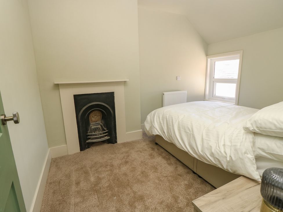 A bedroom with a bed and fireplace at 8 Manor Villas in Totland Bay