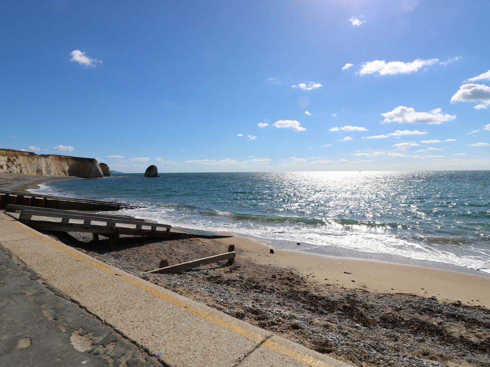 A beach with ocean waves and cliffs at 8 Manor Villas Totland Bay
