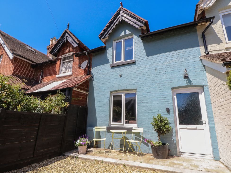 An outdoor view of a blue house with garden chairs at 8 Manor Villas Totland Bay