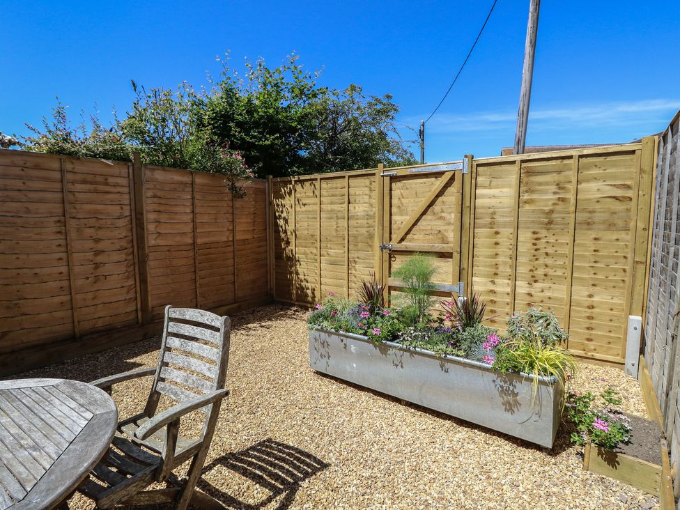 A garden with gravel, a table, and a chair at 8 Manor Villas Totland Bay