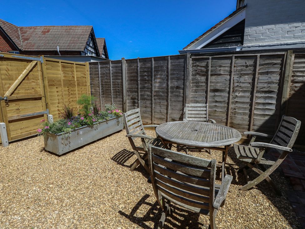 A garden with a table and chairs and a planter at 8 Manor Villas Totland Bay