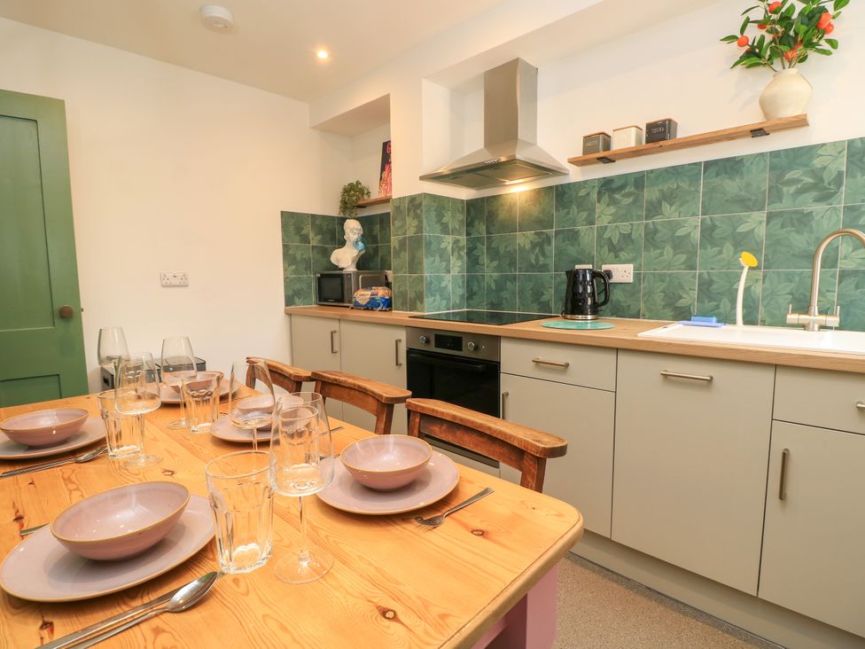 A kitchen with dining area and various appliances at 8 Manor Villas Totland Bay