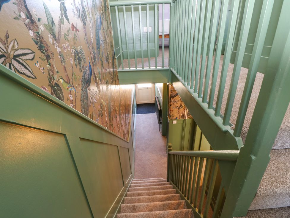 A staircase with green walls and a decorative wallpaper at 8 Manor Villas Totland Bay