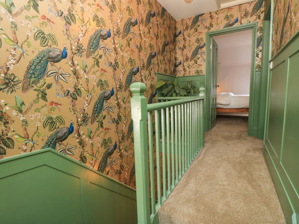 A hallway with patterned wallpaper and green staircase at 8 Manor Villas in Totland Bay
