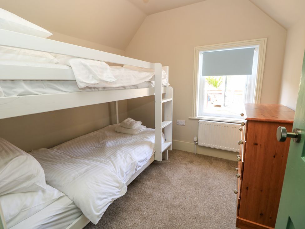 A bedroom with a bunk bed and a dresser at 8 Manor Villas in Totland Bay