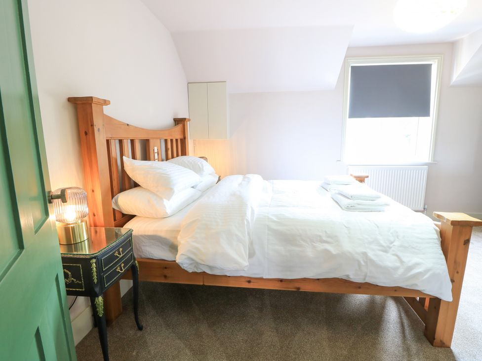 A bedroom with a wooden bed and nightstand at 8 Manor Villas in Totland Bay