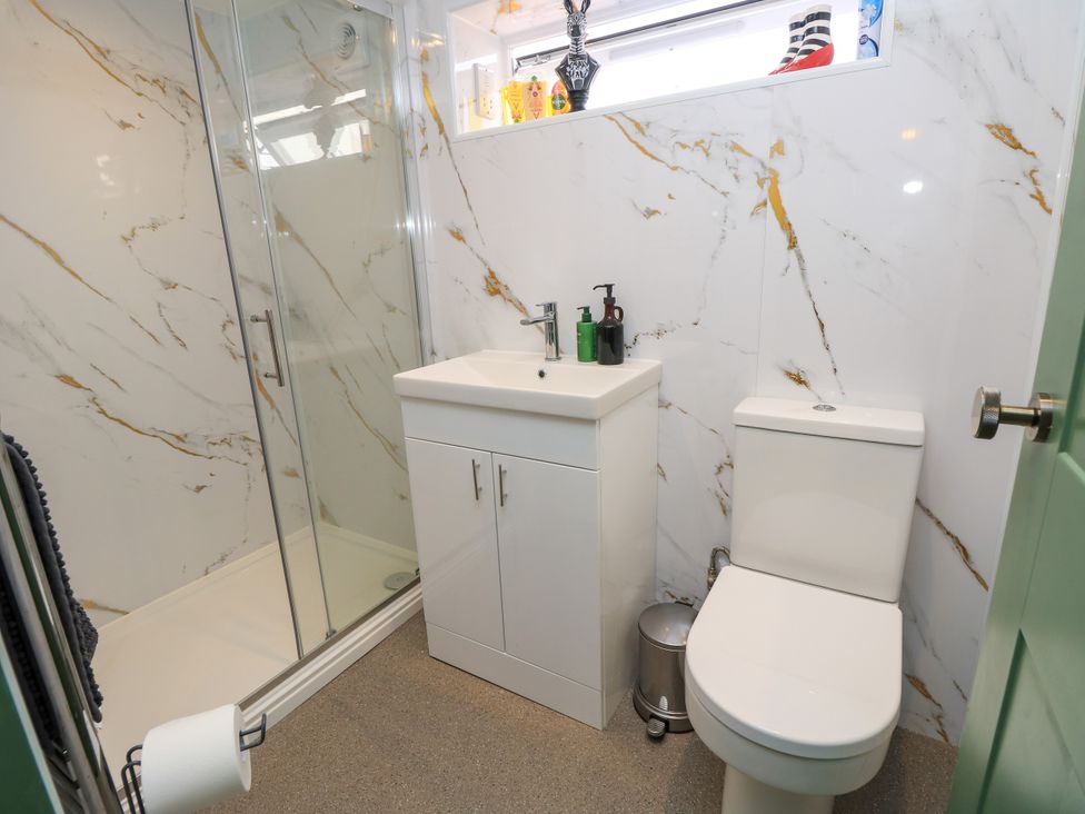 A bathroom with a shower, sink, and toilet at 8 Manor Villas Totland Bay