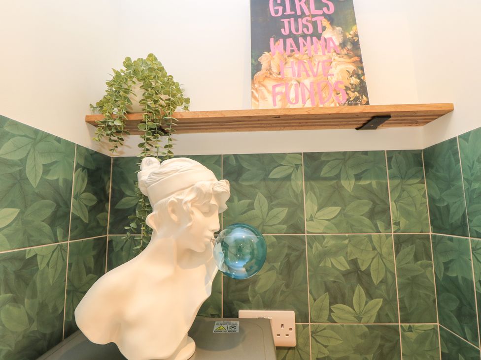 A bathroom featuring a bust, plant, and a poster at 8 Manor Villas in Totland Bay