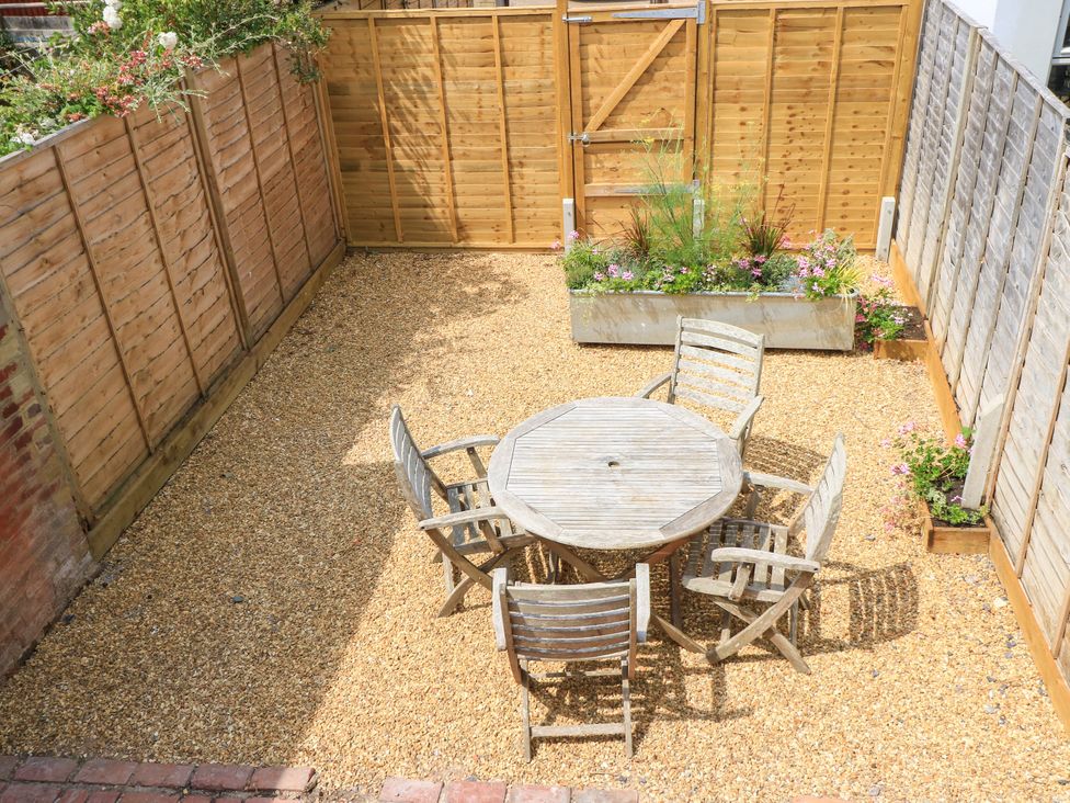 A garden with a wooden table and chairs surrounded by gravel at 8 Manor Villas Totland Bay