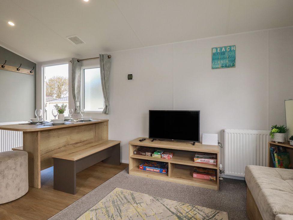 A living room with a table and television at Shamrocks Cove Caravan