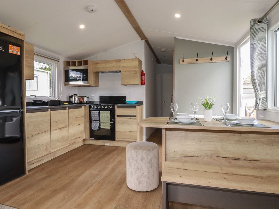 A kitchen with appliances and dining area at Shamrocks Cove Caravan