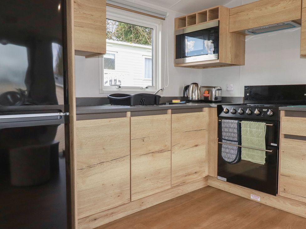 A kitchen with appliances and cabinets at Shamrocks Cove Caravan