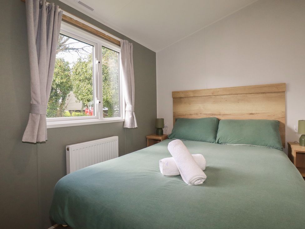 A bedroom with a bed and window at Shamrocks Cove Caravan