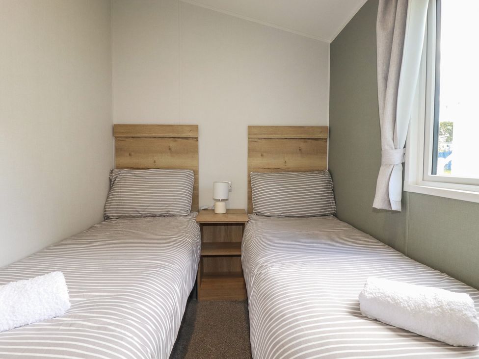 A bedroom with two beds and a bedside table at Shamrocks Cove Caravan