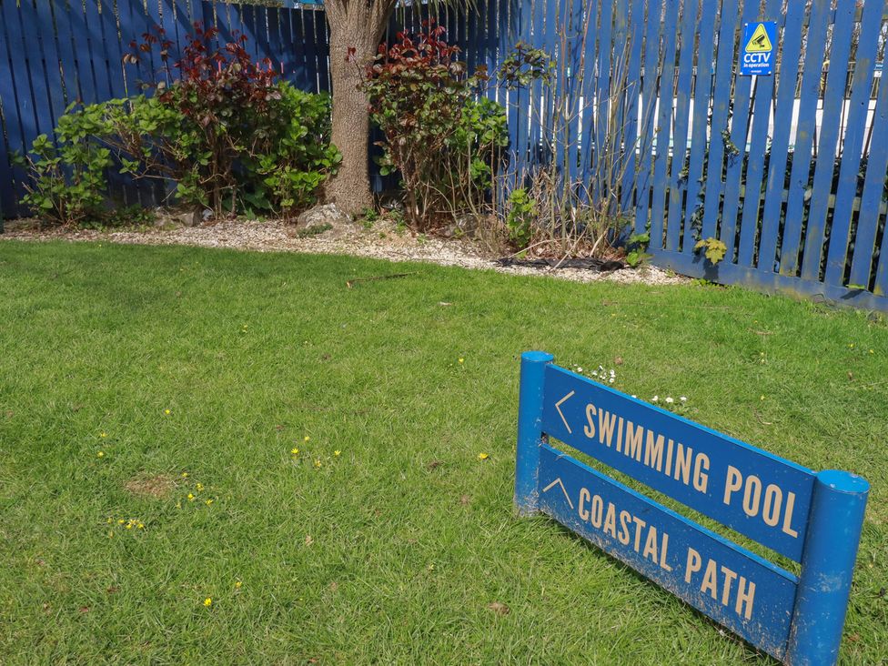 A sign pointing to swimming pool and coastal path at Shamrocks Cove Caravan 