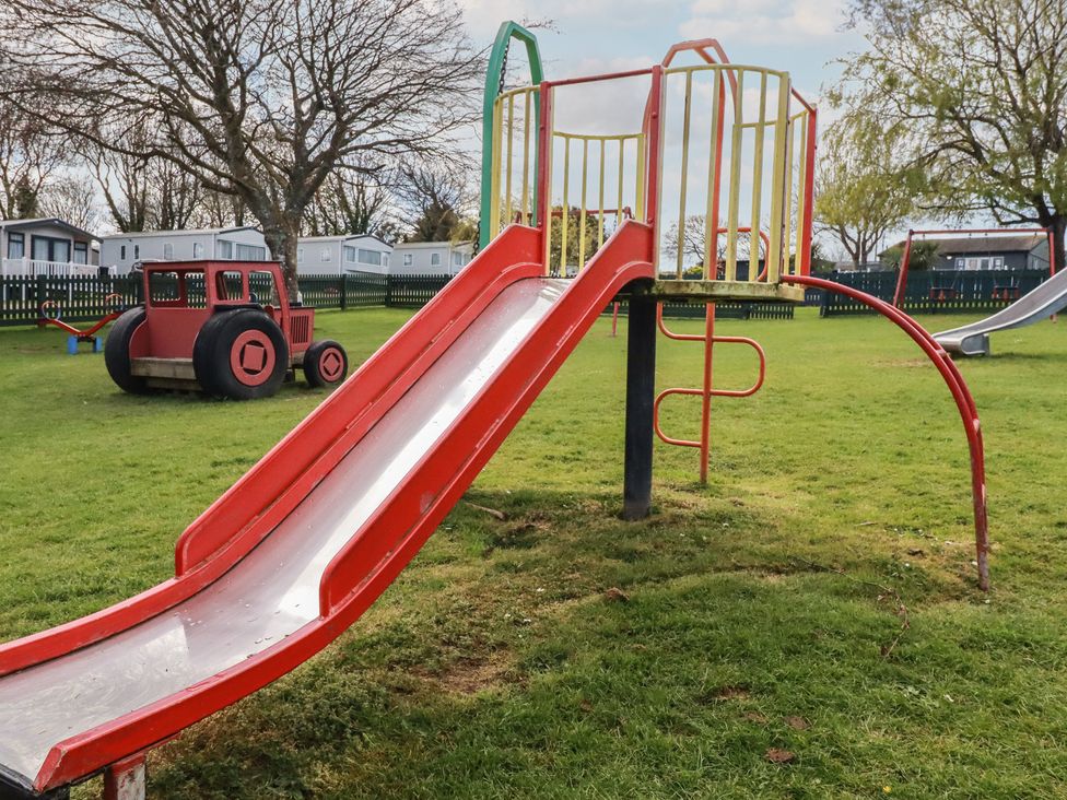 A playground with a slide and toy tractor at Shamrocks Cove Caravan in 