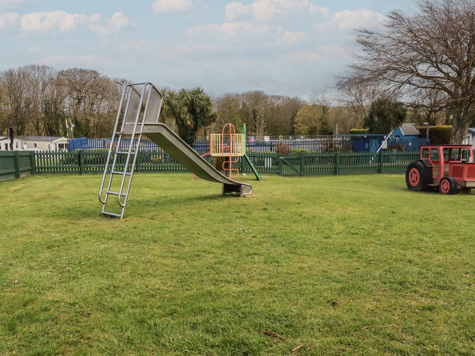 A slide and playground equipment in a grassy area at Shamrocks Cove Caravan