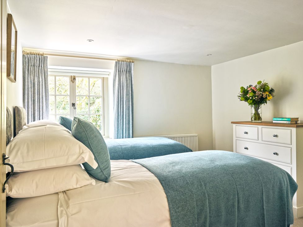 A bedroom with two beds and a dresser at Gitcombe Coach House in Totnes