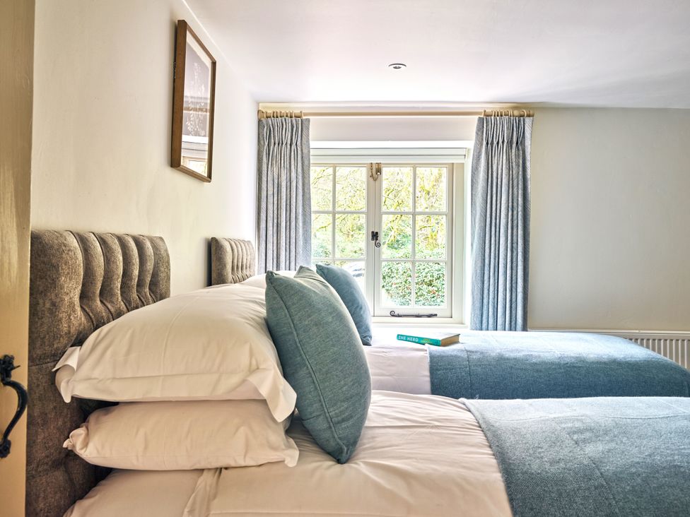 Two beds with pillows and a window at Gitcombe Coach House in Totnes
