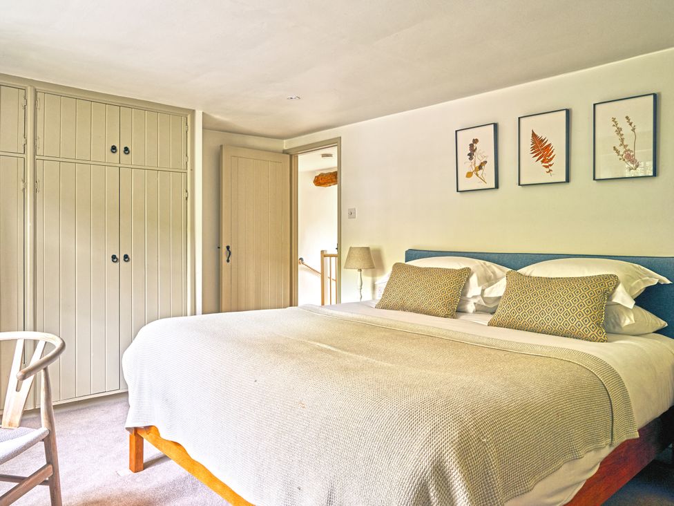 A bedroom with a bed and wardrobe at Gitcombe Coach House in Totnes