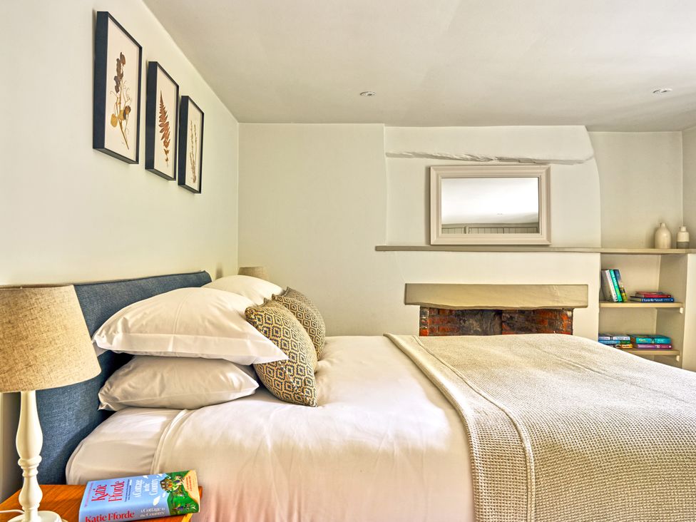 A bedroom with a bed, lamp, and shelf at Gitcombe Coach House in Totnes