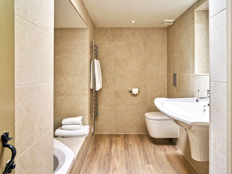 A bathroom with a bathtub, toilet, and sink at Gitcombe Coach House in Totnes