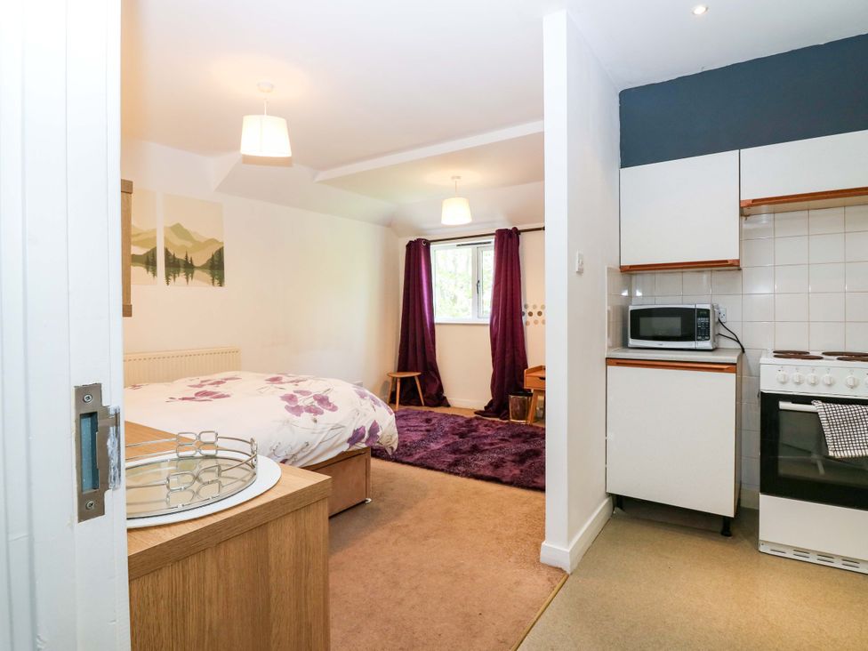 A bedroom with a bed, kitchen area and window at Apartment 1 in Dyce