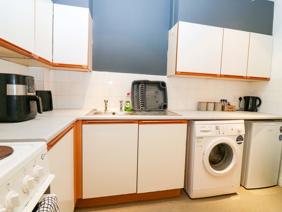 A kitchen with a sink, washing machine, and appliances at Apartment 1 in Dyce