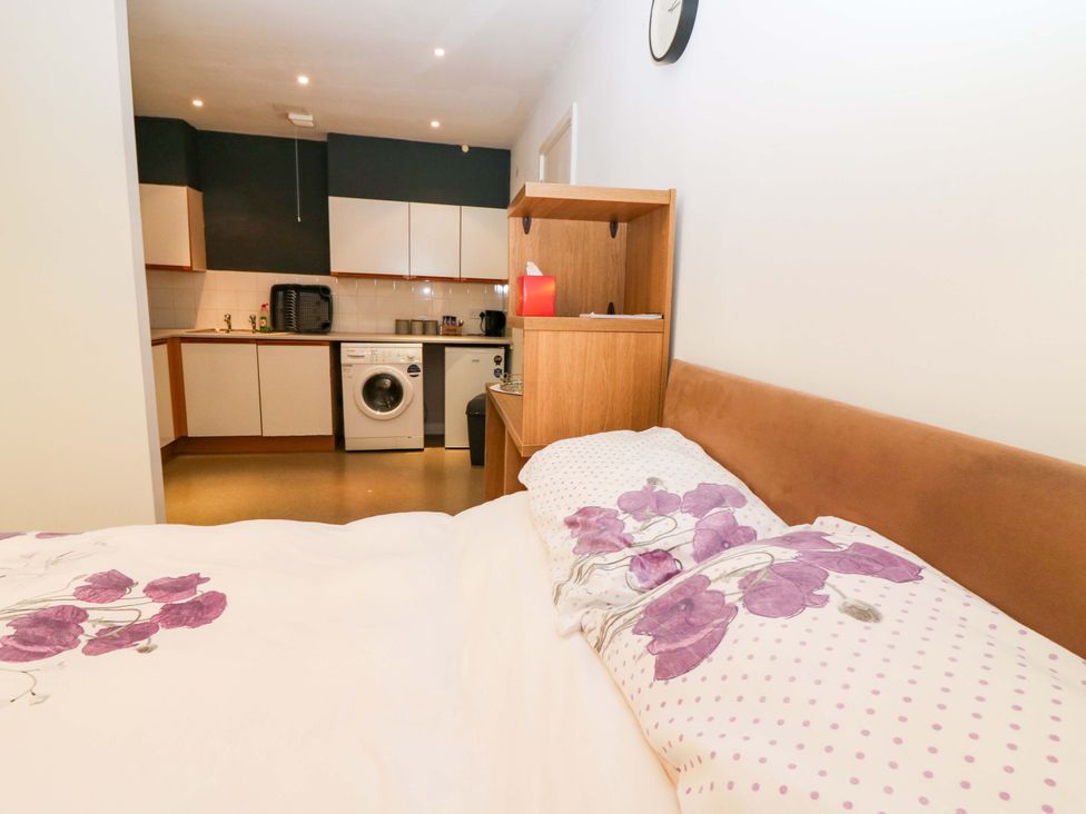 A bedroom with a kitchen visible in the background at Apartment 1 in Dyce