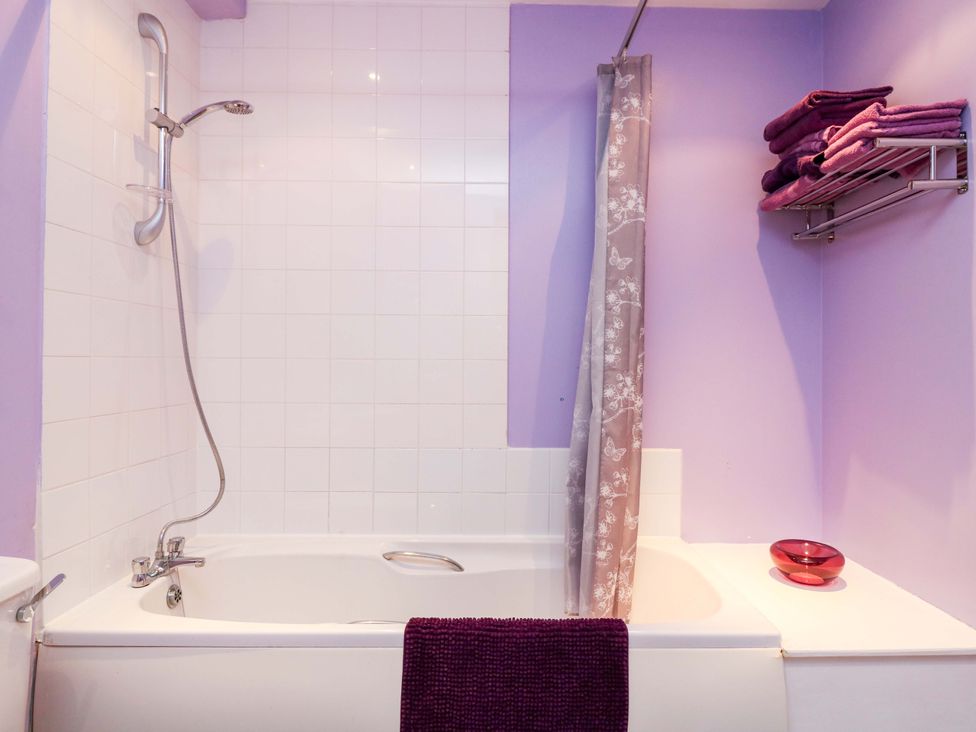 A bathroom with a bathtub and towels at Apartment 1 in Dyce