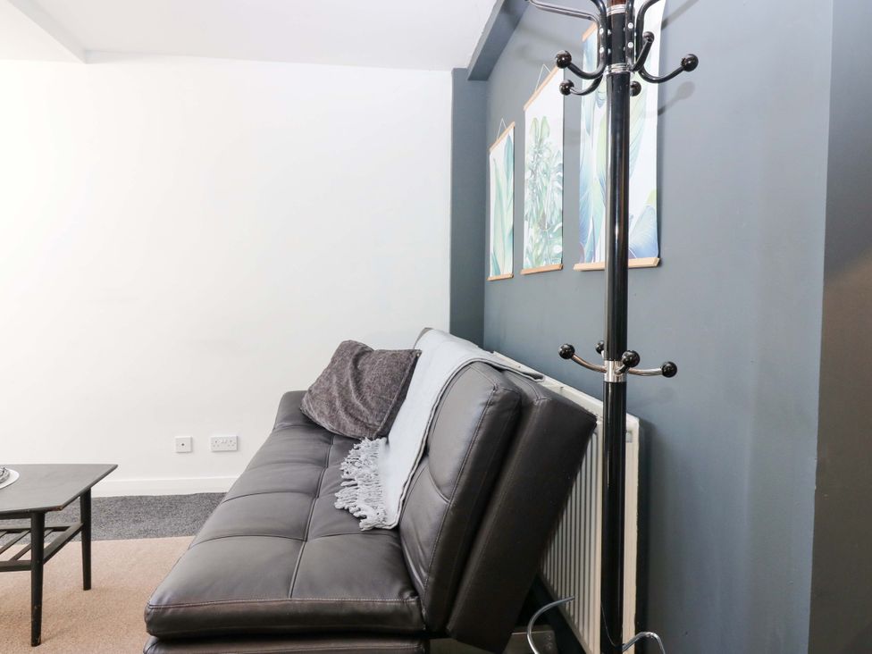 A living room with a sofa and coat rack at Apartment 2 in Dyce