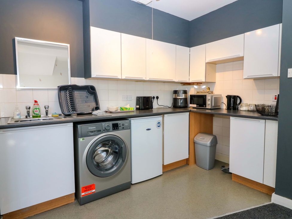 A kitchen with a washing machine and microwave at Apartment 2 in Dyce